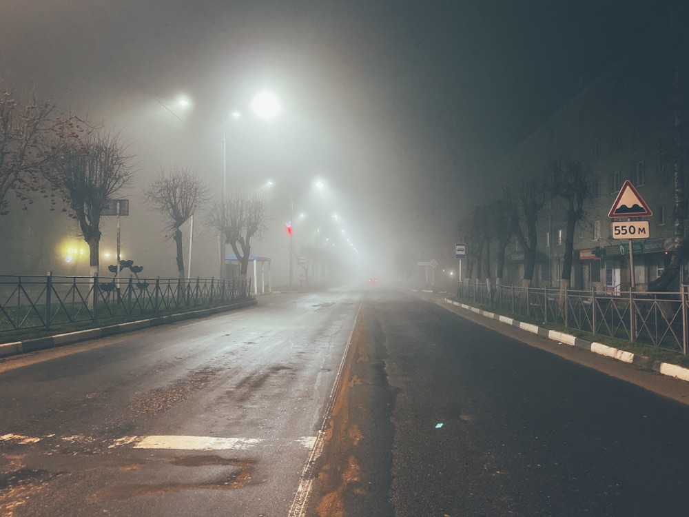 Fotografia illustrativa di repertorio: strada vuota illuminata di notte nella nebbia fitta